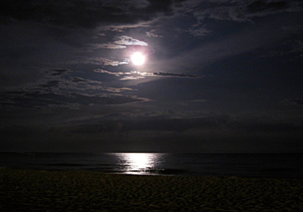 Un riflesso della luna nell'acqua sulla spiaggia di Castelldefels